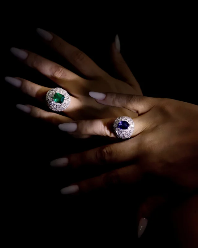An emerald-cut emerald and an oval blue sapphire, each set at the center of a dome of pear-cut and marquise-cut diamonds. 
Two rings, two colors, the same Italian goldsmithing mastery.

Collezione Colore 24095BST-29315BZ